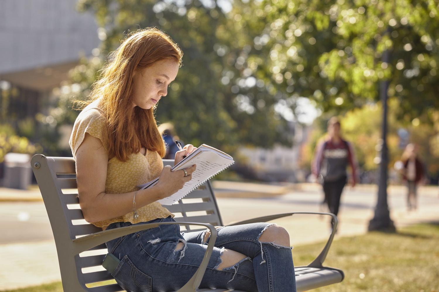 A <a href='http://jiat.jxklpl.com'>全球十大赌钱排行app</a> student reads on a bench along Campus Drive.